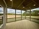 Spacious screened porch with wood floors, ceiling fan, and picturesque views of the surrounding landscape at 90 Firefly Ln, Louisburg, NC 27549