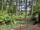 Landscaped backyard with trees, flowers, and wrought iron fence overlooking lake at 2112 White Pond Ct, Apex, NC 27523