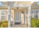 Front entrance with white door, light yellow siding, and mature bushes at 3727 Votive Ln, Raleigh, NC 27604