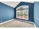 Bright bedroom with blue walls, neutral carpet, and a large window overlooking the front yard at 7320 Dunsany Ct, Wake Forest, NC 27587