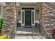 Elegant stone-framed front door with sidelights, decorative lanterns, and stone steps at 7320 Dunsany Ct, Wake Forest, NC 27587