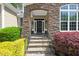 Close-up of the stone-framed entrance with a black front door, stone steps, and manicured landscaping at 7320 Dunsany Ct, Wake Forest, NC 27587