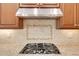Close-up of a kitchen stove with granite countertops and a stainless steel vent hood at 7320 Dunsany Ct, Wake Forest, NC 27587