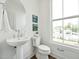 Modern powder room with a pedestal sink, round mirror, and view of the pool at 524 Billingshurst Way, Knightdale, NC 27545