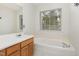 Bathroom with a large bathtub, vanity, and a window at 10947 Pendragon Pl, Raleigh, NC 27614