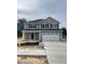 Charming two-story home with a stone-accented facade and an attached two-car garage and freshly poured driveway at 203 Lake Edge Dr, Lillington, NC 27546