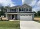 Charming two-story home with gray and blue siding, black shutters, and a two-car garage at 203 Lake Edge Dr, Lillington, NC 27546