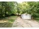 View of the detached garage at the end of the driveway and backyard area with greenery at 2612 Ashe St, Durham, NC 27703
