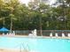 Outdoor pool with clear blue water, surrounded by lounge chairs and a safety fence at 2662 Sledge Rd, Louisburg, NC 27549