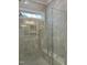Modern bathroom shower featuring light gray marbled tile, built-in shelving, seating, and glass door at 318 Hinton St, Apex, NC 27502