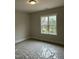 Bedroom featuring large window with wooded views and neutral carpet covered with plastic sheeting at 318 Hinton St, Apex, NC 27502