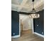 Dining room featuring a coffered ceiling, modern chandelier, dark gray walls, and hardwood floors at 318 Hinton St, Apex, NC 27502