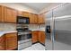 Kitchen with wood cabinets, stainless steel refrigerator, oven, and microwave with tiled backsplash at 2621 Oldgate Dr # 105, Raleigh, NC 27604