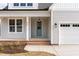 Charming front porch with white columns, a brick base, a blue front door, and an attached two-car garage at 57 Nottoway Ln, Wendell, NC 27591