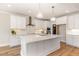 Bright kitchen featuring a large island, white cabinetry, quartz counters, and stainless steel appliances at 57 Nottoway Ln, Wendell, NC 27591