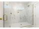 Gorgeous, marble-tiled walk-in shower features glass doors, gold hardware, and built in shelves at 57 Nottoway Ln, Wendell, NC 27591