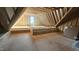 Unfinished attic featuring wood beams and a small window at 7934 Wexford Waters Ln, Wake Forest, NC 27587