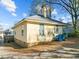 Rear view of the home with a chimney, blue trash cans, and leafy trees shading the yard at 1108 Taylor St, Durham, NC 27701