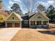 Charming home with a manicured lawn, gabled roof, wood garage doors, and inviting front porch at 113 Meadowglades Ln, Cary, NC 27518