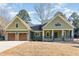 Charming home with a manicured lawn, gabled roof, wood garage doors, and inviting front porch at 113 Meadowglades Ln, Cary, NC 27518