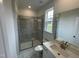 Modern bathroom with marble tile in the shower, white vanity and sink, and framed mirror at 1528 Goldfinch Perch Ln, Knightdale, NC 27545