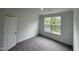 A bedroom with gray carpet, and white walls and trim, with a large window at 1528 Goldfinch Perch Ln, Knightdale, NC 27545