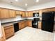 Well-lit kitchen featuring wood cabinets, black appliances, and tile flooring at 4712 Fox Fern Ln, Raleigh, NC 27604