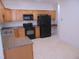 Kitchen with wood cabinets, granite countertops, black appliances, and tile floor at 4712 Fox Fern Ln, Raleigh, NC 27604