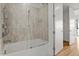 Bathroom with a tub-shower featuring glass doors, tile surround, and view into the bedroom at 523 S West # 305, Raleigh, NC 27601