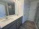 Modern bathroom with double sink vanity, gray cabinets, quartz countertop, framed mirror, and glass shower at 6328 Granite Quarry Dr, Raleigh, NC 27610
