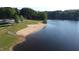 Beautiful aerial view of lake with a sandy beach, green spaces, picnic shelter, and mature trees on a sunny day at 1119 Sagamore Dr, Louisburg, NC 27549