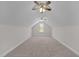 Carpeted attic space featuring two ceiling fans, sloped ceilings, and a window at 1119 Sagamore Dr, Louisburg, NC 27549