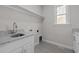 Bright laundry room features a gray tile floor, a window, shelving, and gray countertop at 1119 Sagamore Dr, Louisburg, NC 27549