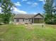 View of the house's back exterior and screened porch surrounded by lush, green lawn at 1813 Ferrell Meadows Dr, Zebulon, NC 27597