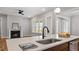 Kitchen island featuring a sink, and quartz countertop open to the living area with fireplace at 224 Wash Hollow Dr, Wendell, NC 27591