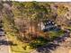 Aerial view showing a large house on a wooded lot with a paved driveway at 3 Acornridge Ct, Durham, NC 27707
