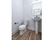 Modern powder room with pedestal sink, white toilet, and wood-look flooring at 707 Colleton Rd, Raleigh, NC 27610