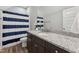 Clean bathroom with granite countertop, dark brown vanity, and blue and white striped shower curtain at 107 York Dr, Oxford, NC 27565