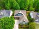 Aerial view of charming blue home, lush front yard, and surrounding green trees at 241 Serenity Hill Cir, Chapel Hill, NC 27516