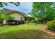 Well-maintained backyard with lush lawn, mature trees, and a view of the home's exterior at 241 Serenity Hill Cir, Chapel Hill, NC 27516