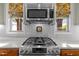 Close up of a stainless gas cooktop and microwave, and two windows with patterned window treatments at 241 Serenity Hill Cir, Chapel Hill, NC 27516
