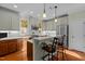 The open kitchen has an island with bar stool seating, stainless steel appliances, pendant lights, and hardwood flooring at 241 Serenity Hill Cir, Chapel Hill, NC 27516