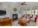 Cozy living room with a fireplace, built in shelves, a ceiling fan, and large windows at 241 Serenity Hill Cir, Chapel Hill, NC 27516