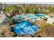 Aerial view of splashpad with blue covering in community pool area surrounded by green trees at 241 Serenity Hill Cir, Chapel Hill, NC 27516