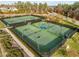 Aerial shot of multiple fenced tennis courts with green surfaces, blue accents and surrounding trees at 241 Serenity Hill Cir, Chapel Hill, NC 27516
