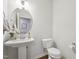 Stylish powder room with pedestal sink, toilet and oval mirror at 524 Brunello Dr, Wake Forest, NC 27587