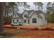 Two-story white brick home with black framed windows and dark roof, set in a wooded area undergoing construction at 6805 Greystone Dr, Raleigh, NC 27615