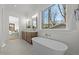 Bright bathroom featuring a soaking tub, double vanity, and scenic backyard views through a large window at 3304 Cheswick Dr, Raleigh, NC 27609