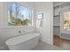 Modern bathroom featuring a soaking tub under a large window and a walk-in closet at 3304 Cheswick Dr, Raleigh, NC 27609