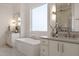 Bright bathroom showcasing the standalone tub, double vanities, a large mirror, and elegant lighting at 1608 Legacy Ridge Ln, Wake Forest, NC 27587